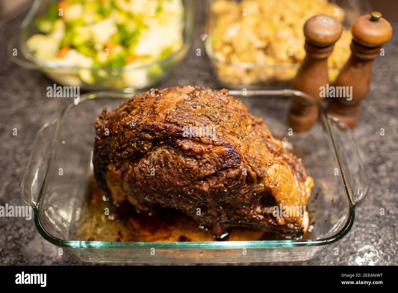 Dîner de rôti de bœuf entrecôté avec salières et poivrières et plats en arrière-plan Banque D'Images