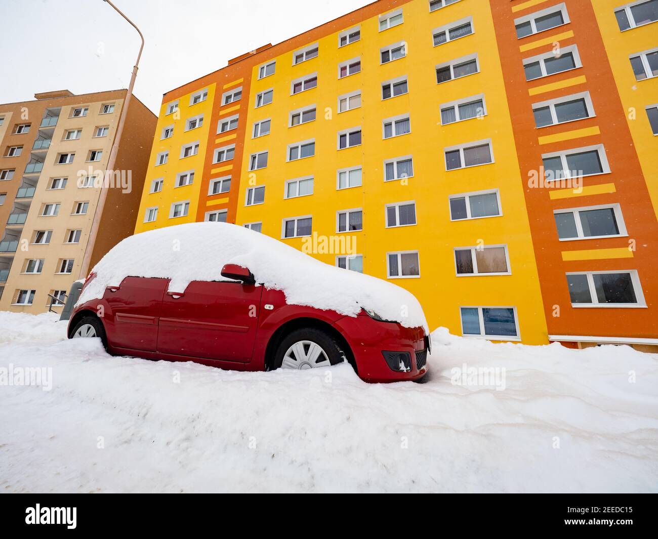 Voiture perdue sous une énorme neige et une maison de résidence jaune orange Dans une rue en hiver Banque D'Images
