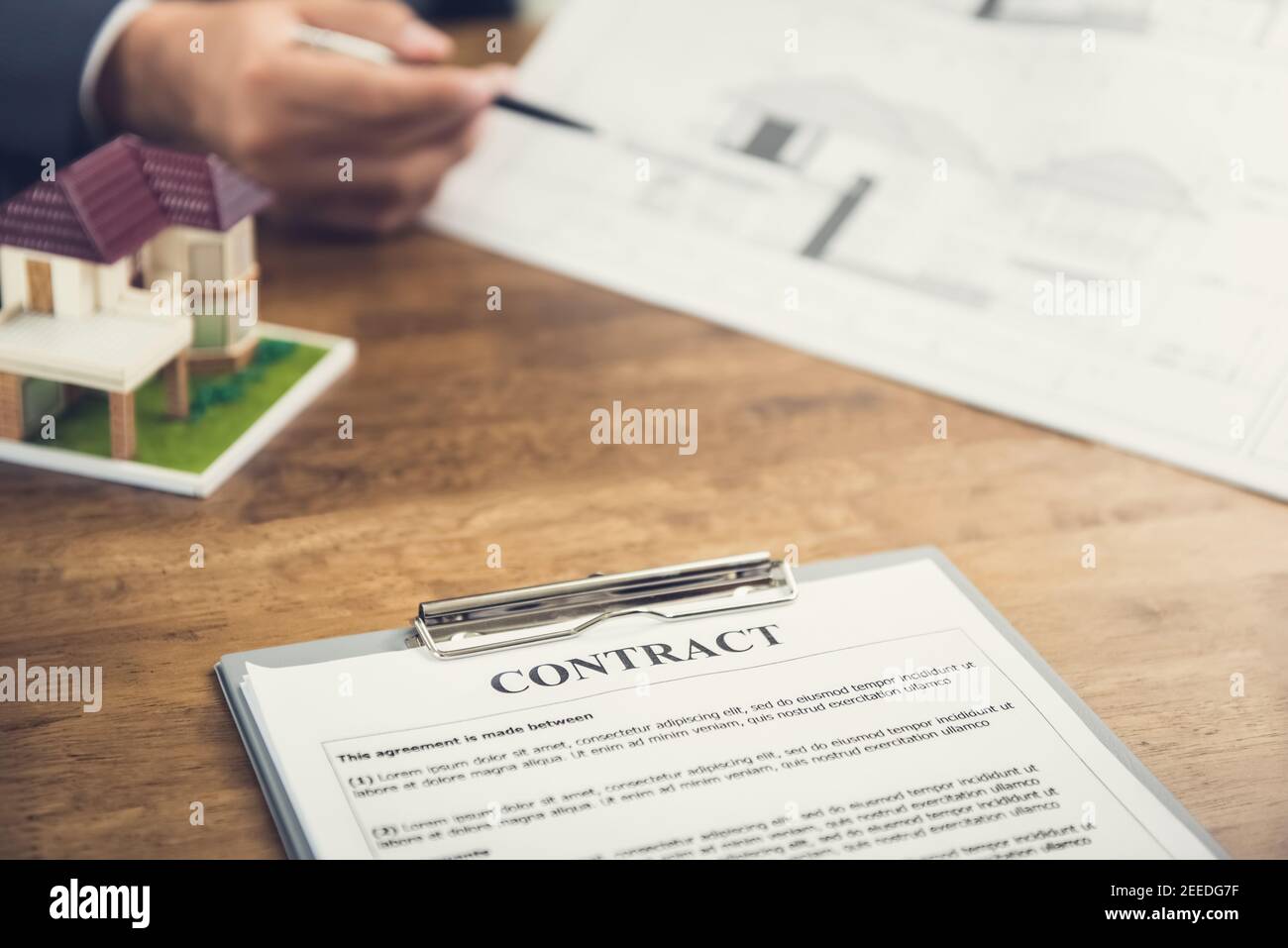 Contrat de papier et modèle de maison sur la table avec flou de main d'homme d'affaires de réviser le plan en arrière-plan - réel concept d'affaires de succession Banque D'Images