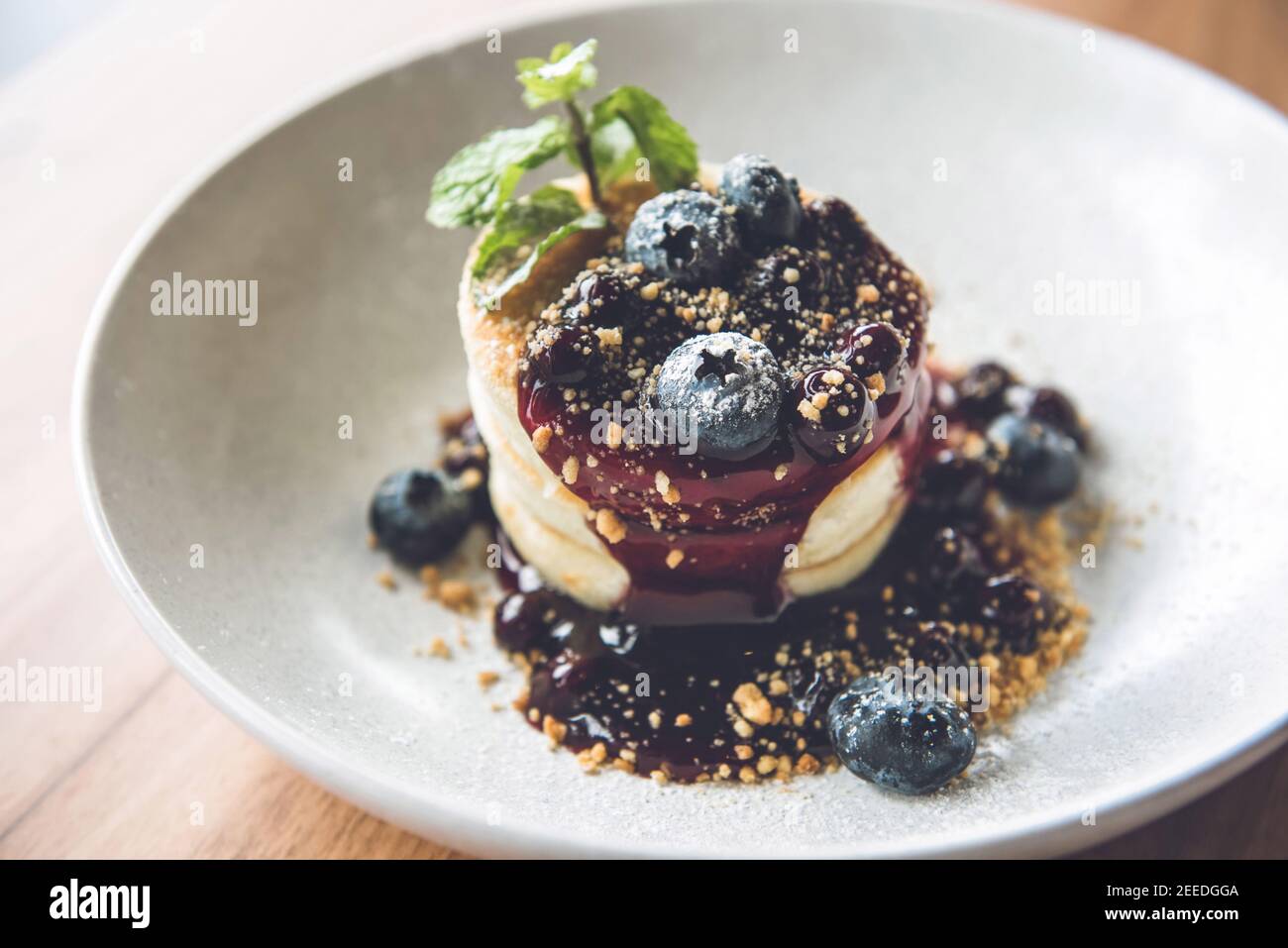 Magnifique pile appétissante de crêpes moelleuses nappées de bleuets frais, de sirop et de biscuits moulés dans une assiette blanche Banque D'Images