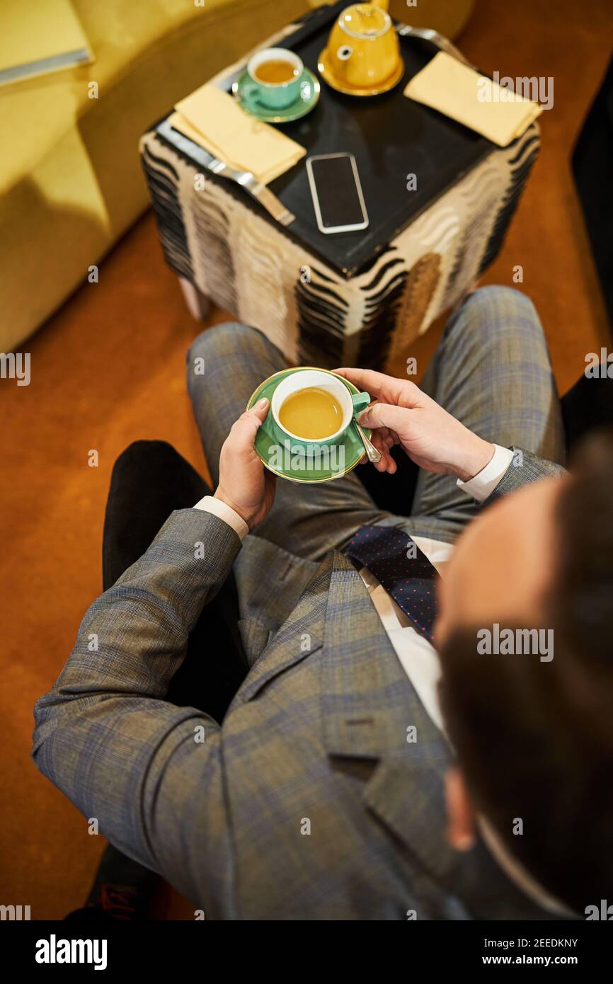 Homme élégant dans un costume tendance buvant du thé Banque D'Images