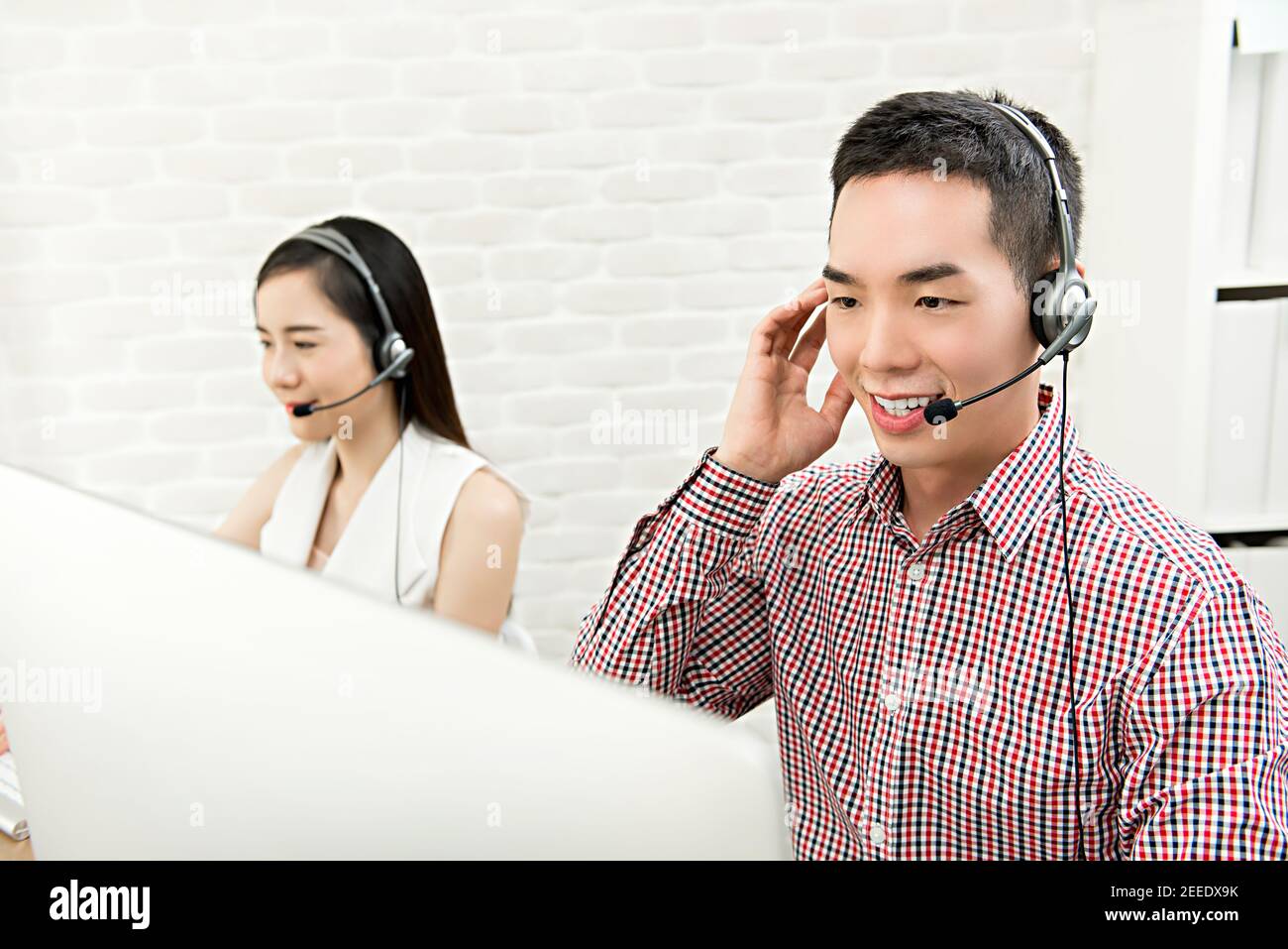 Souriant asiatique homme télémarketing agent du service clientèle travaillant dans l'appel centrez avec son équipe Banque D'Images