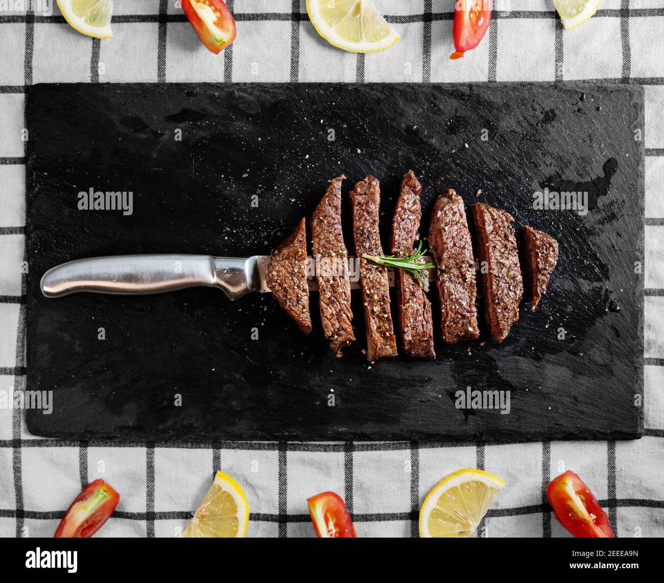Steak de bœuf grillé, filet de bœuf sur une assiette de pierre noire avec tomates et citron Banque D'Images