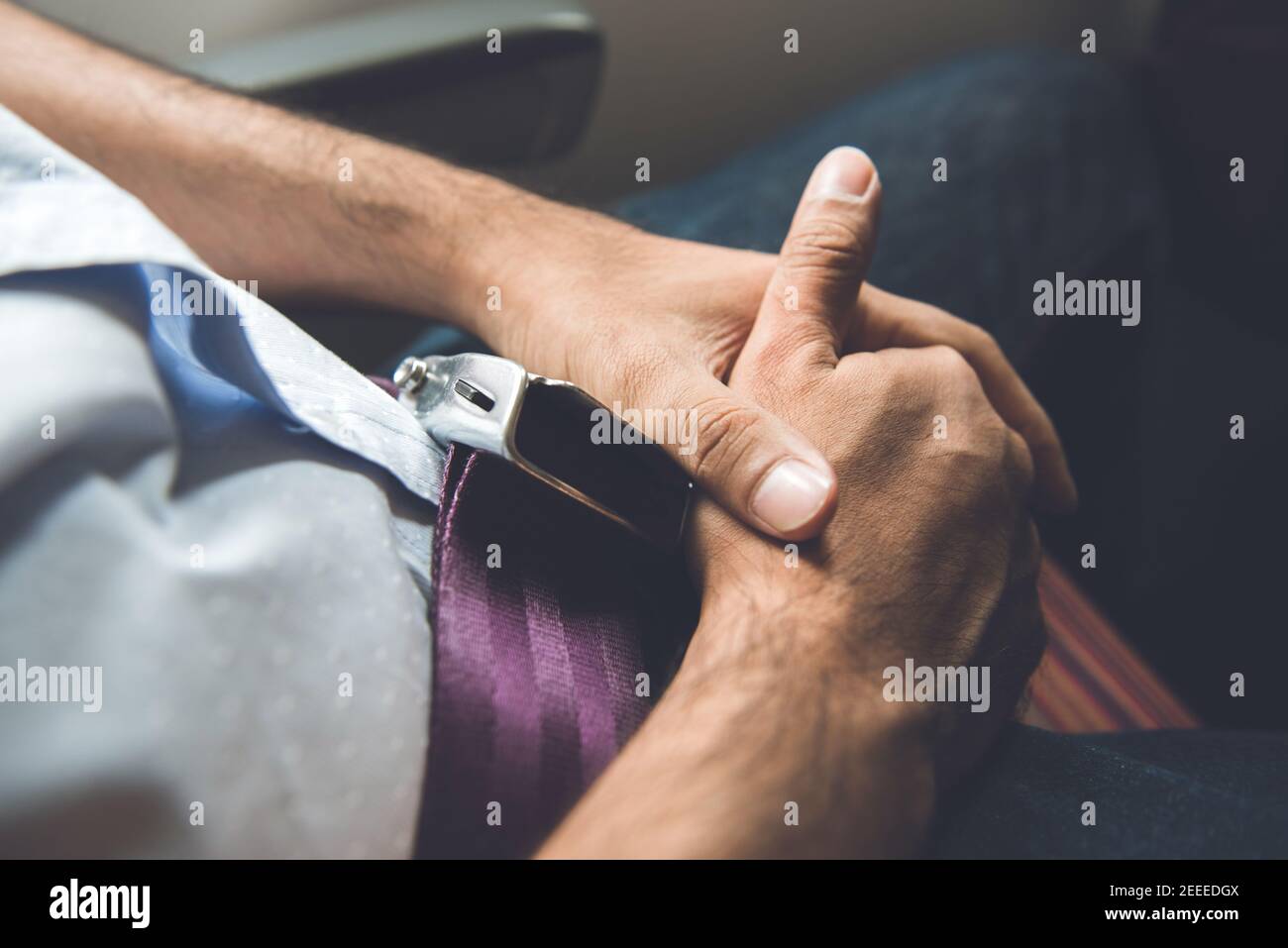 Homme passager assis dans l'avion avec ceinture de sécurité bouclée pour un vol en toute sécurité Banque D'Images