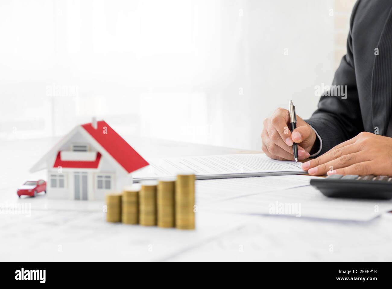 Homme d'affaires signant le document avec l'argent et le modèle de maison sur le tableau - concepts financiers immobiliers et immobiliers Banque D'Images