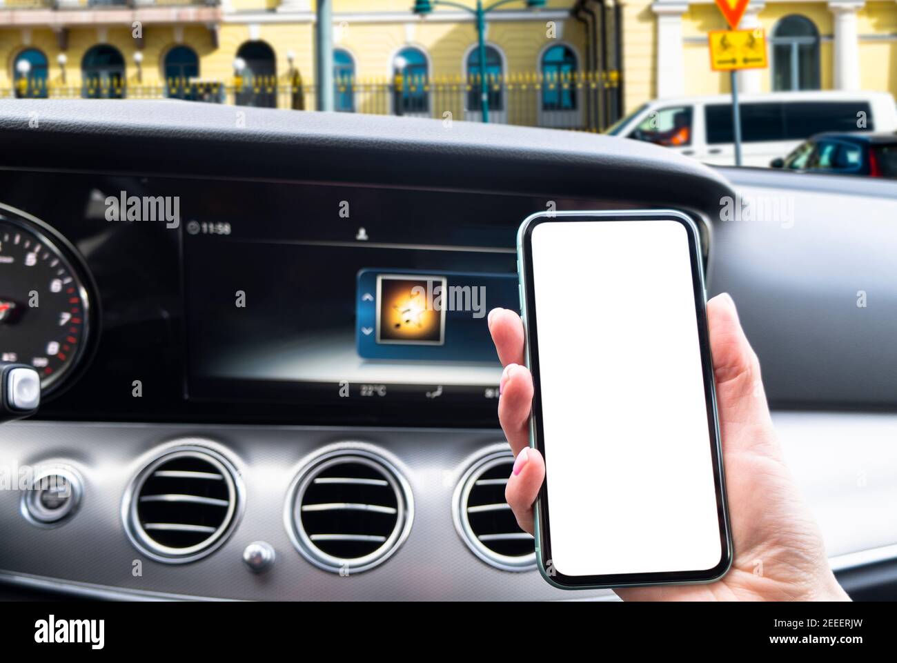 Main féminine utilisant un smartphone en voiture. Smartphone en voiture pour la navigation ou le GPS. Téléphone portable avec écran blanc isolé. Écran vide vide. Copier sp Banque D'Images