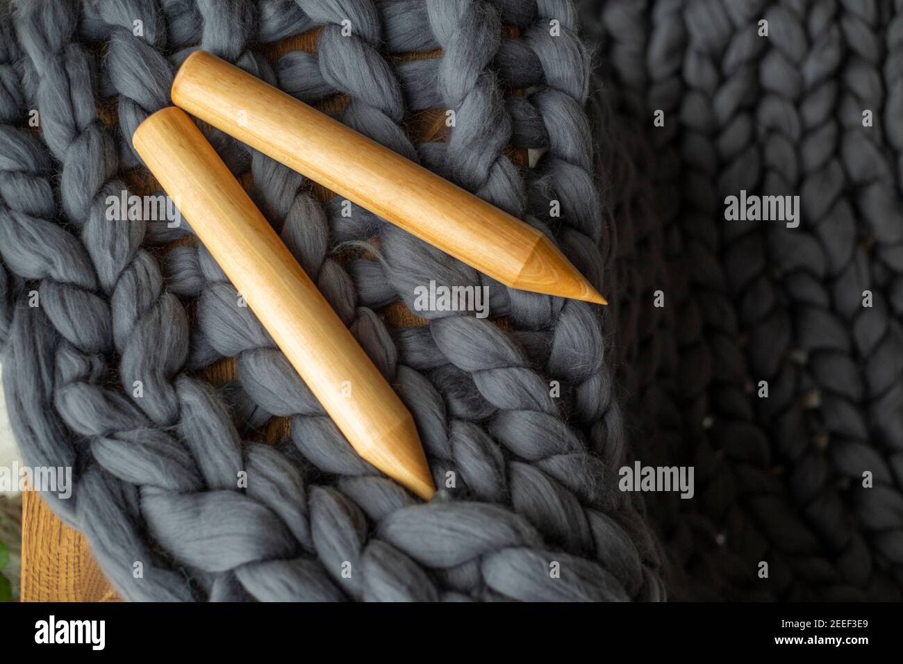 Deux aiguilles à tricoter en bois couchés sur de la laine mérinos grise Banque D'Images