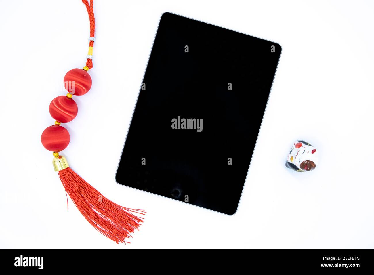 Tablette à écran noir et décor chinois du nouvel an sur fond blanc. Festival oriental présent photo vue du dessus. Nœud rouge et chat chanceux avec écran vierge Banque D'Images