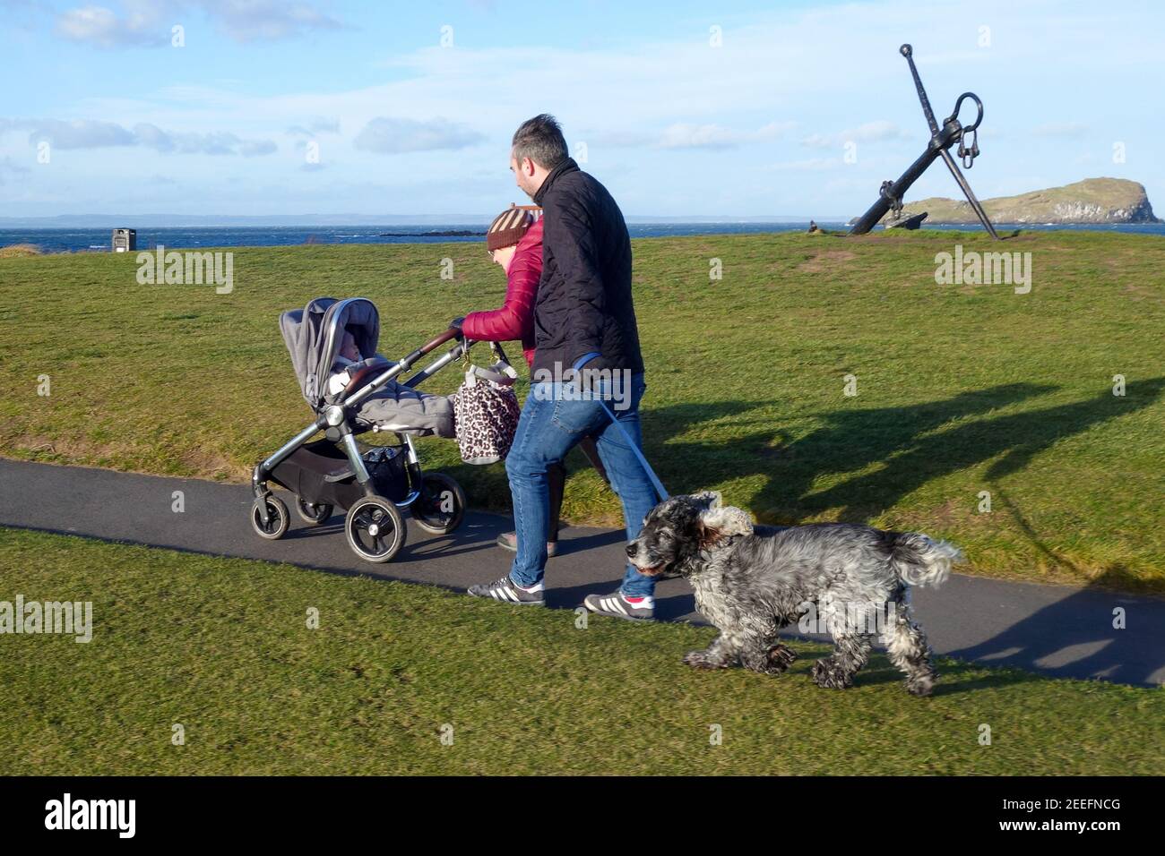 Grand-mère poussant le pram, et le père marchant avec le chien Banque D'Images