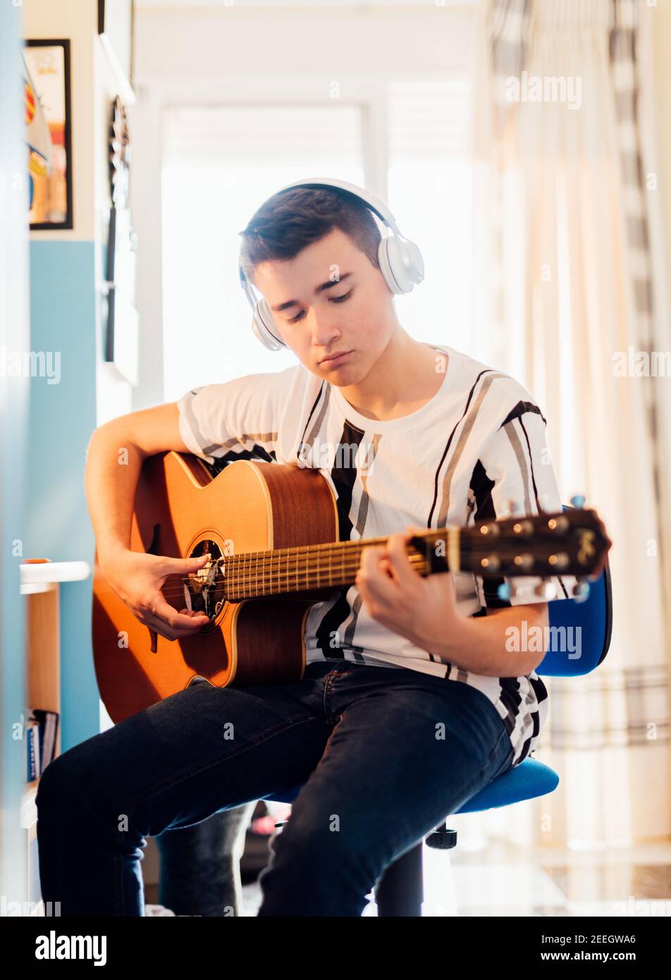 Garçon prenant des leçons de guitare en ligne dans votre chambre. Concept de technologie. Banque D'Images