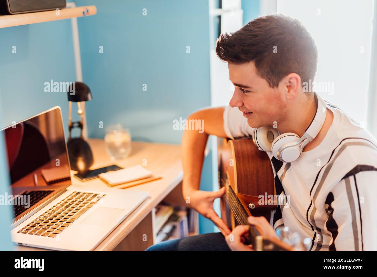 Garçon prenant des leçons de guitare en ligne dans votre chambre. Concept de technologie. Banque D'Images
