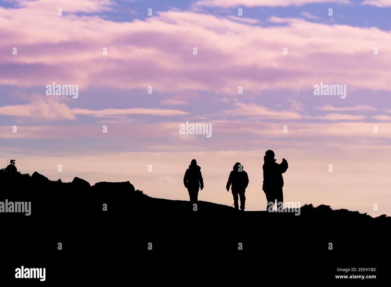 Les marcheurs se sont fait silhouetés par la lumière du soir en marchant le long du sentier de la côte à Newquay, dans les Cornouailles. Banque D'Images