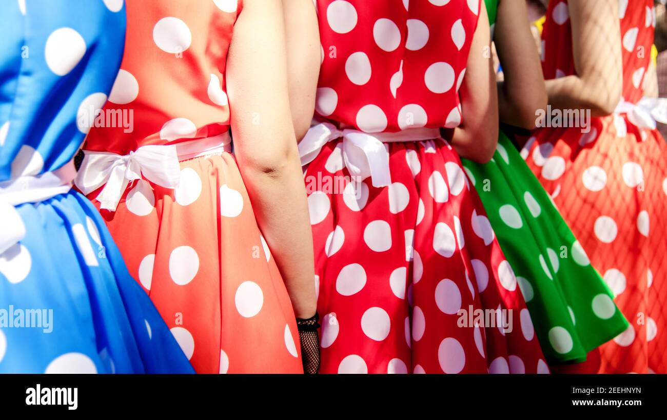 Groupe de jeunes filles dans des robes colorées avec des pois. Mode rétro des robes rouges et bleues avec pois blancs. Banque D'Images