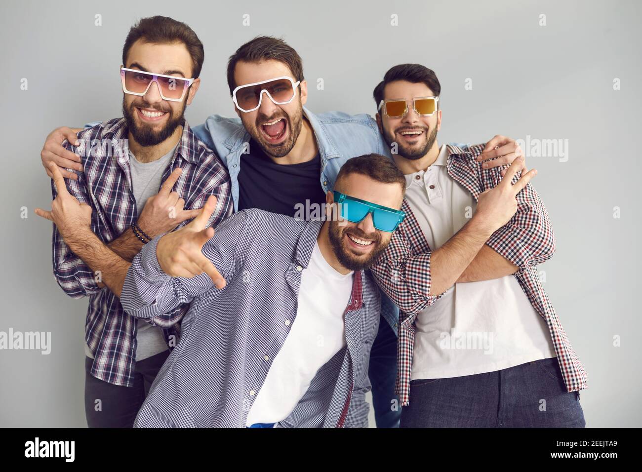 Groupe de jeunes amis dans des lunettes de soleil ayant le plaisir et la pose pour une photo amusante en studio Banque D'Images