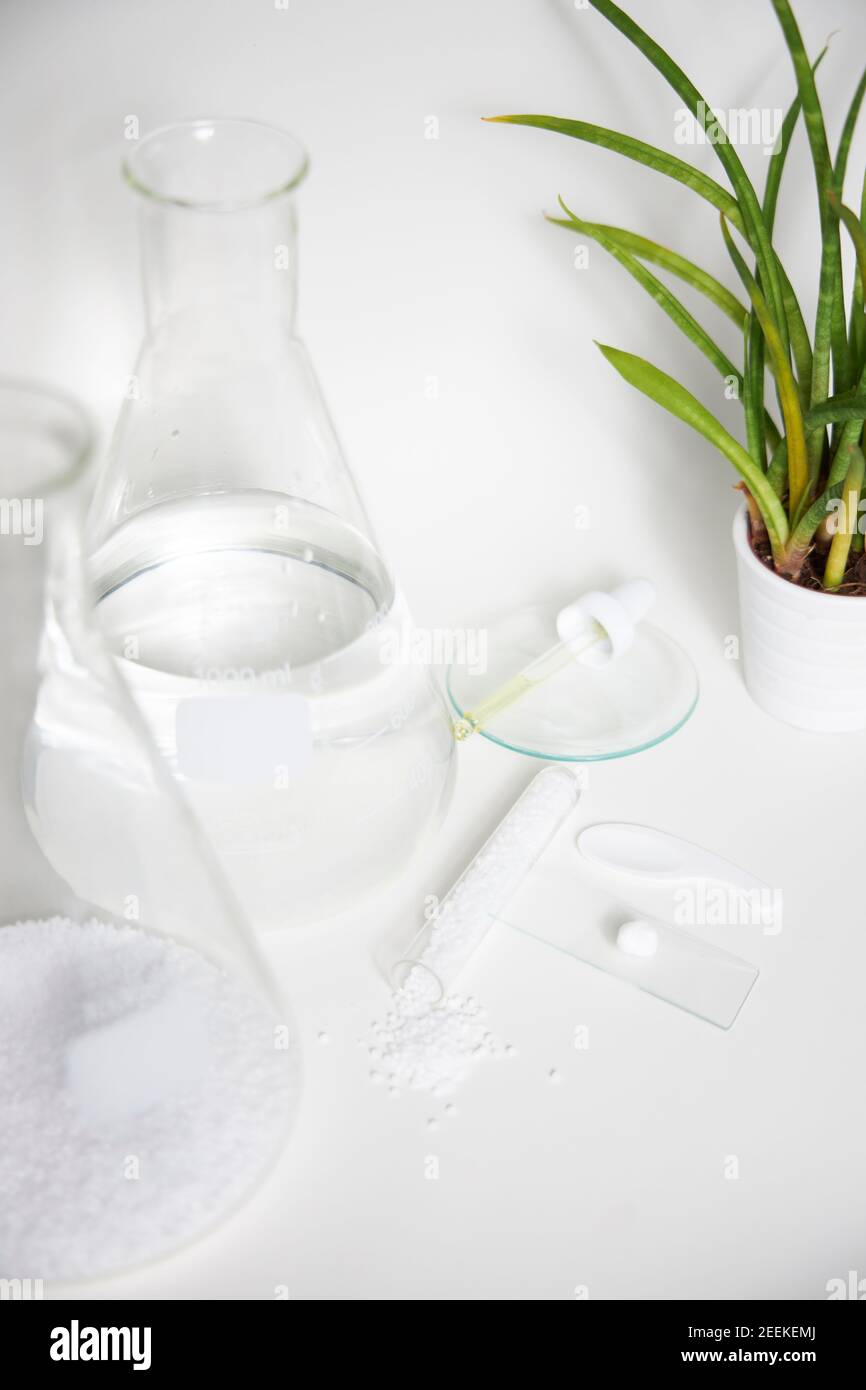 Laboratoire cosmétique ou chimique abstrait. Préparation d'un produit cosmétique. Flacons de produits chimiques transparents sur fond blanc. Tir vertical Banque D'Images