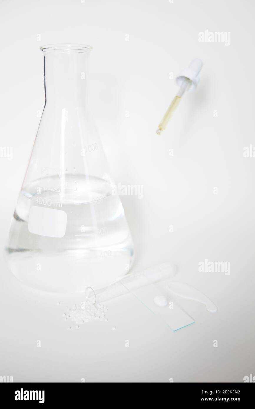 Laboratoire cosmétique ou chimique abstrait. Préparation d'un produit cosmétique. Flacons de produits chimiques transparents sur fond blanc. Tir vertical Banque D'Images