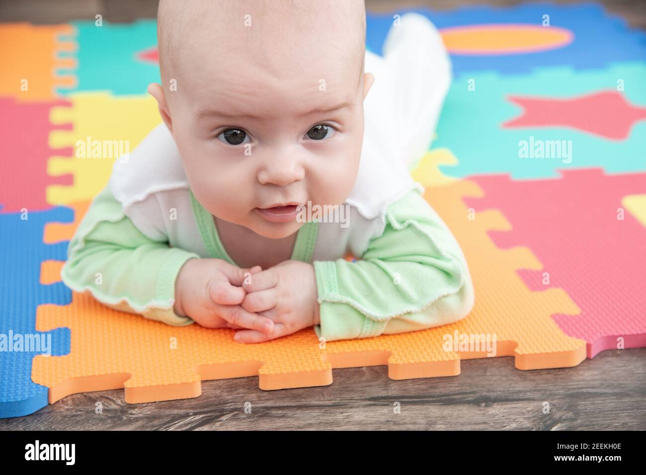 Rire enfant sur un puzzle de tapis de caoutchouc coloré pour jouer mousse eva avec figures géométriques Banque D'Images