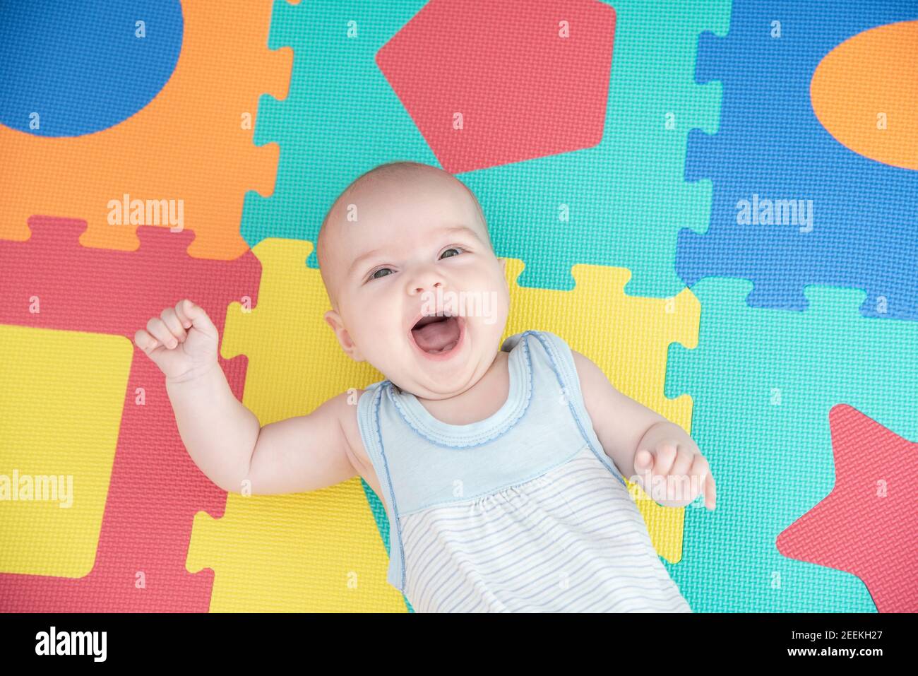 Rire enfant sur un puzzle de tapis de caoutchouc coloré pour jouer mousse eva avec figures géométriques Banque D'Images