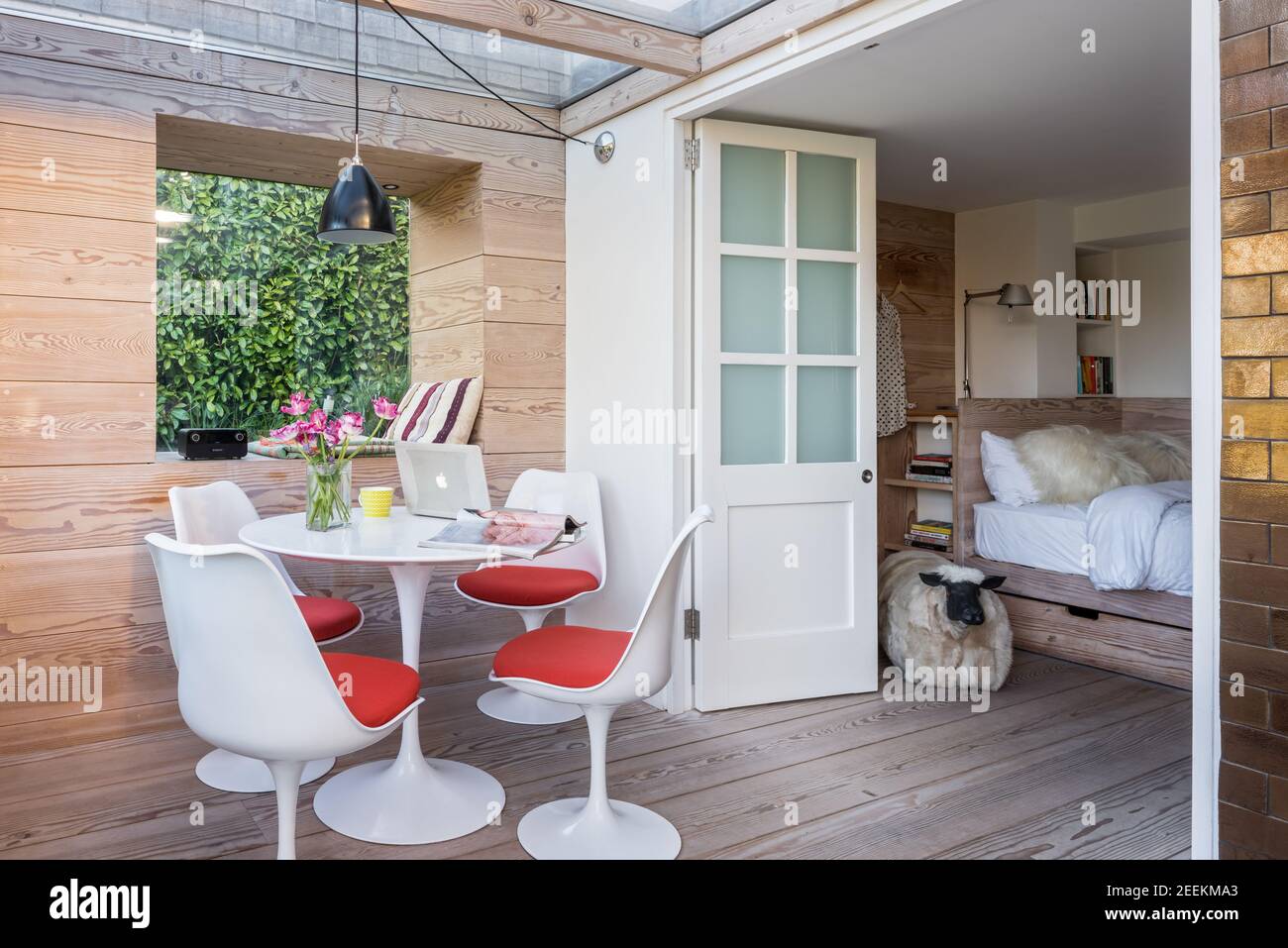Studio jardin avec Eero Saarinen Tulip table et chaises, murs, sol et lit à Douglas Fir by Dominic Ash Banque D'Images