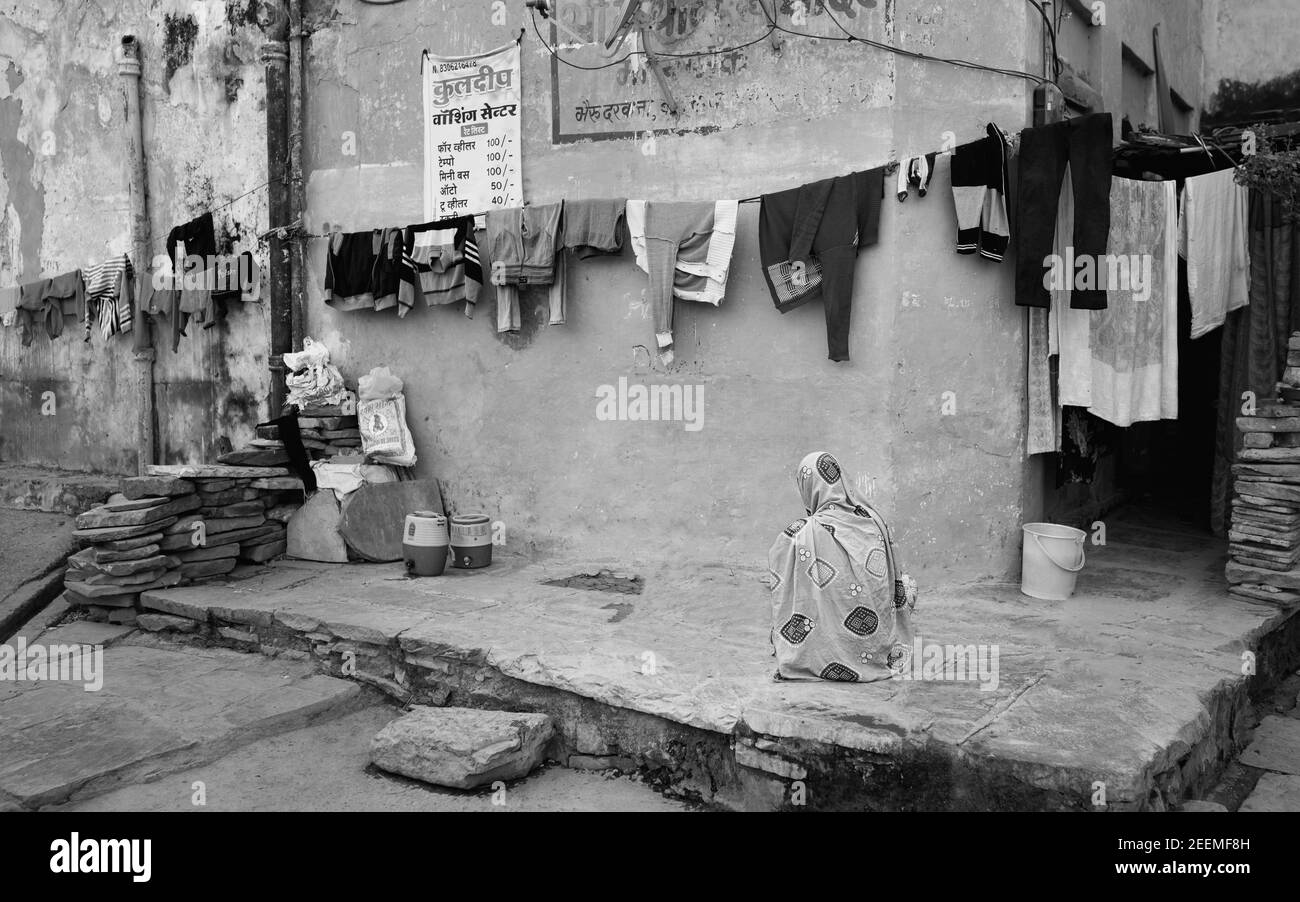 Femme, avec petite entreprise de blanchisserie, assis à côté de vêtements sécher dehors dans la rue à Bundi, Rajasthan, Inde. Banque D'Images