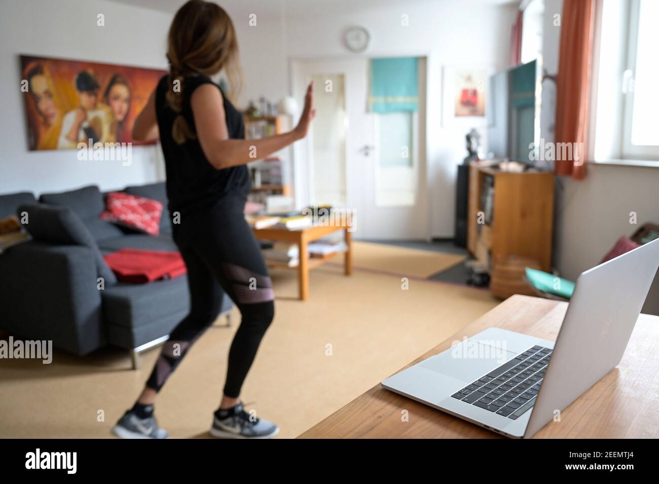 ALLEMAGNE, Hambourg, corona pandémie, jeune femme faisant du sport à la maison avec la diffusion en ligne de club de sport, Apple macbook écran avec Zumba danse session Banque D'Images