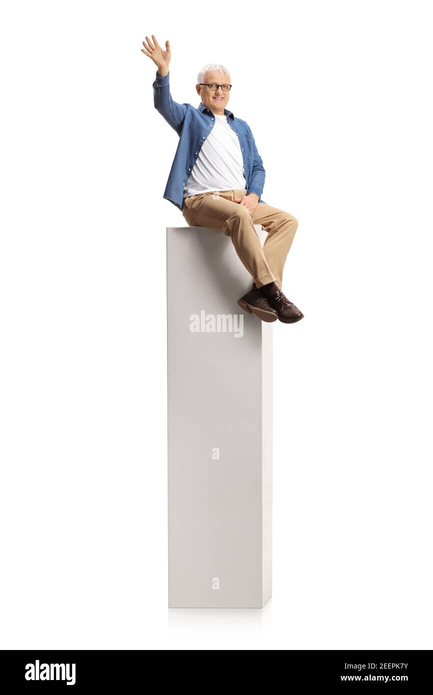 Homme mûr souriant assis sur une colonne et agitant à caméra isolée sur fond blanc Banque D'Images