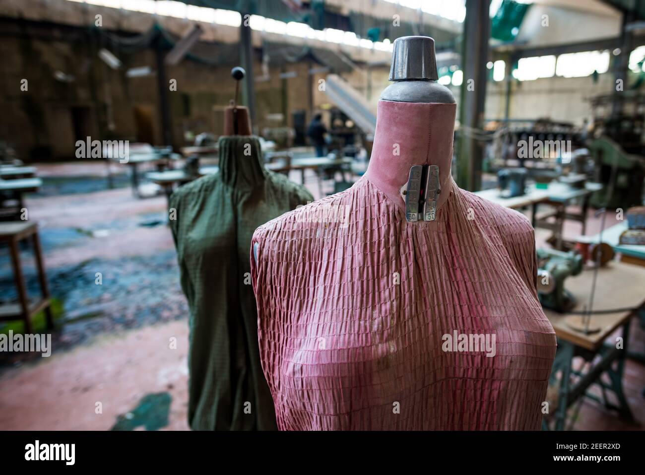 Gros plan sur les mannequins d'un tailleur rose et vert délavé Dans une ancienne et abandonnée usine de textile italienne Banque D'Images