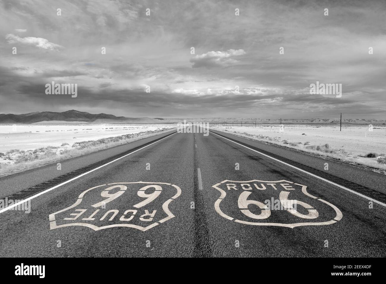 Partie solitaire de la route 66 avec des nuages spectaculaires de tempête dans le désert en noir et blanc. Banque D'Images