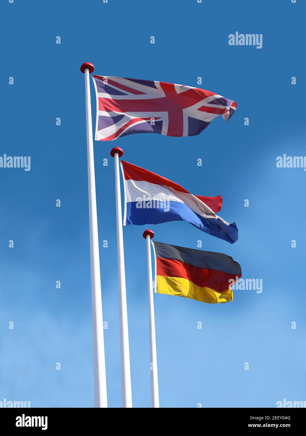 Drapeaux du Royaume-Uni, de la France et de l'Allemagne. Le drapeau du Royaume-Uni est en haut. Fond bleu ciel. Banque D'Images