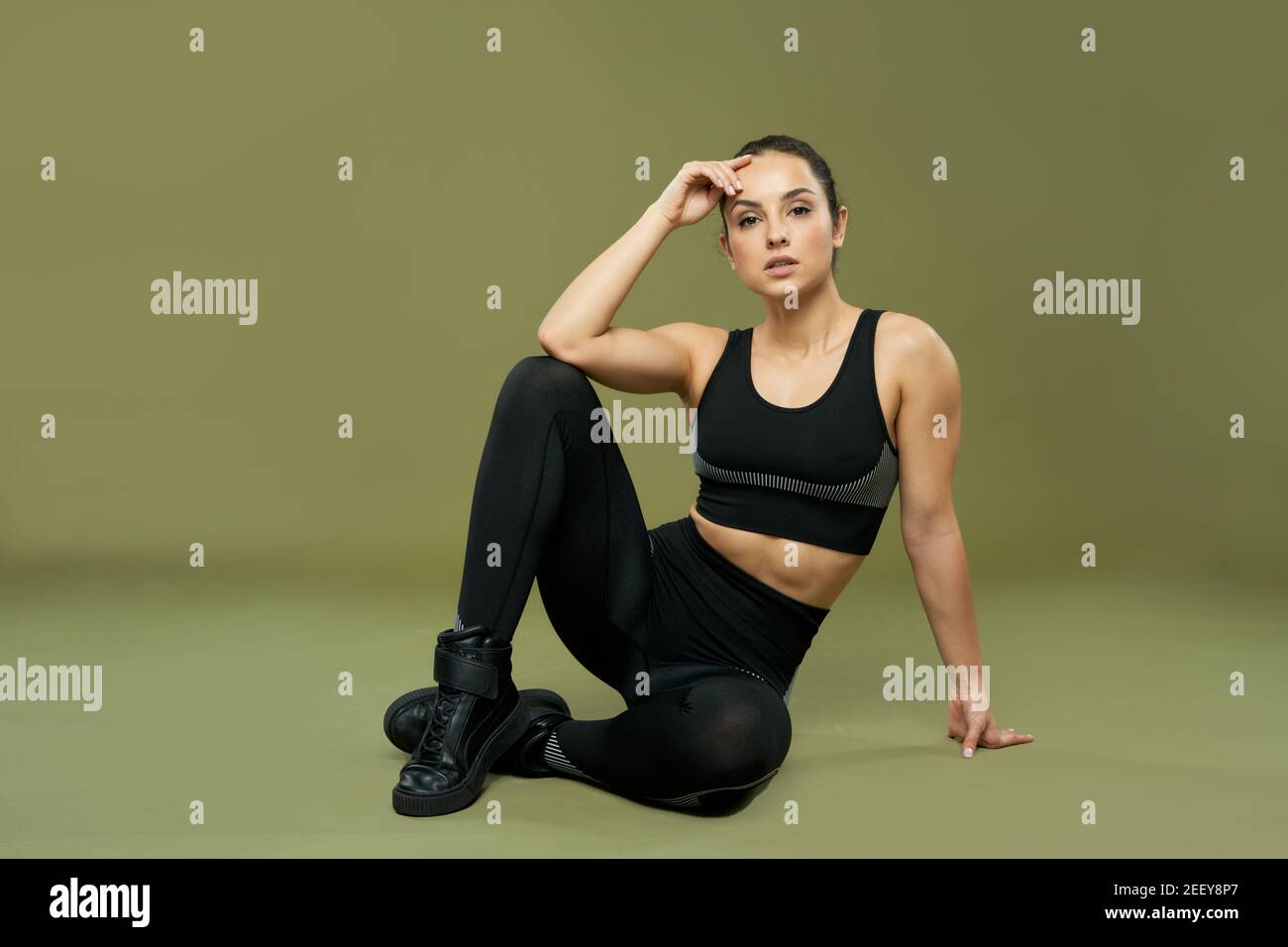 Charmante femme en tenue d'entraînement sport costume touchant le front et  regardant l'appareil photo avec une expression sérieuse. Isolé sur fond  vert Photo Stock - Alamy