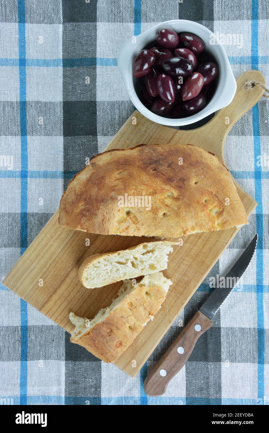 Olives Kalamon et pain lagana sur planche à découper en bois Banque D'Images
