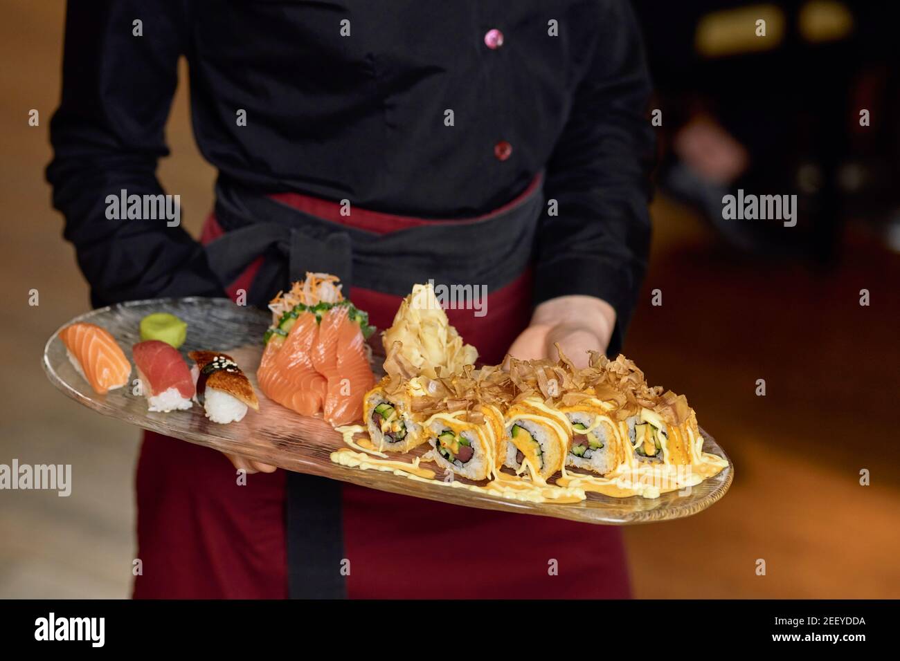 Photo rognée d'un sushi appétissant mis entre les mains de une serveuse professionnelle Banque D'Images