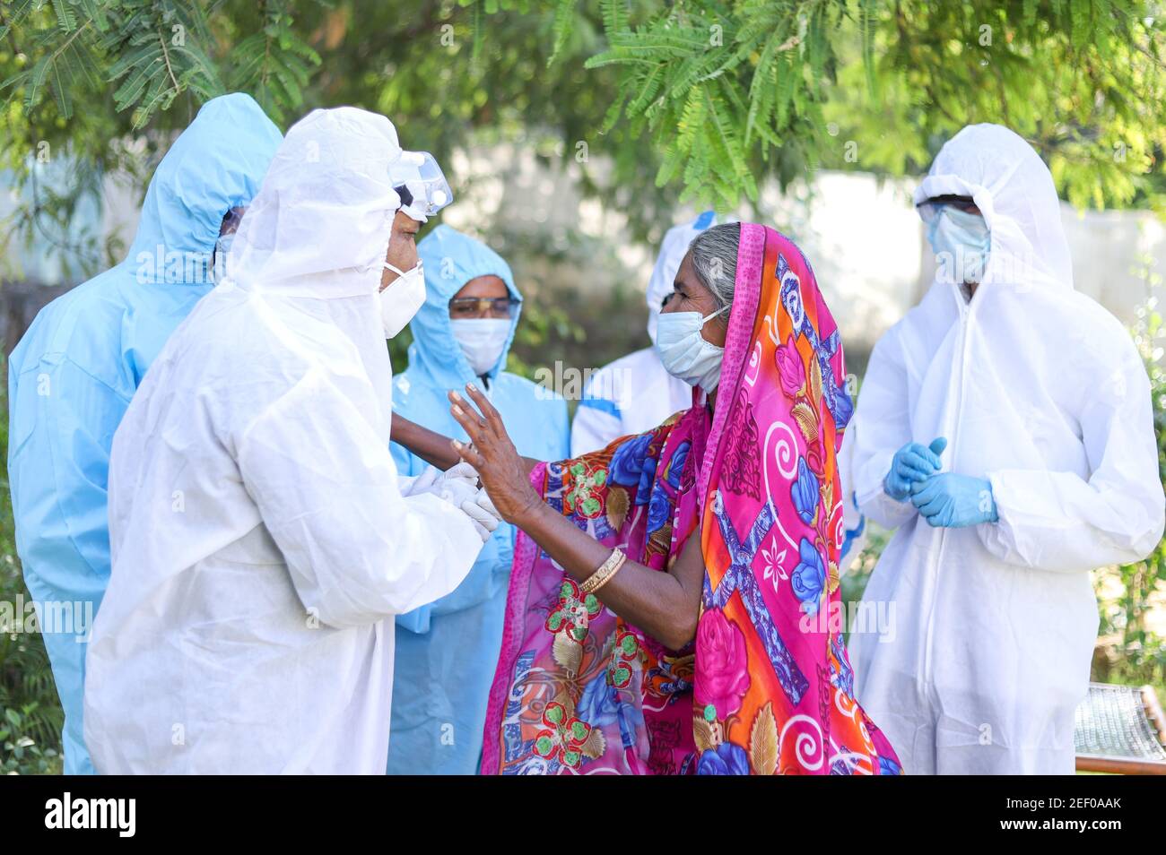 Femme indienne âgée communiquant avec des travailleurs médicaux portant des vêtements de protection Banque D'Images