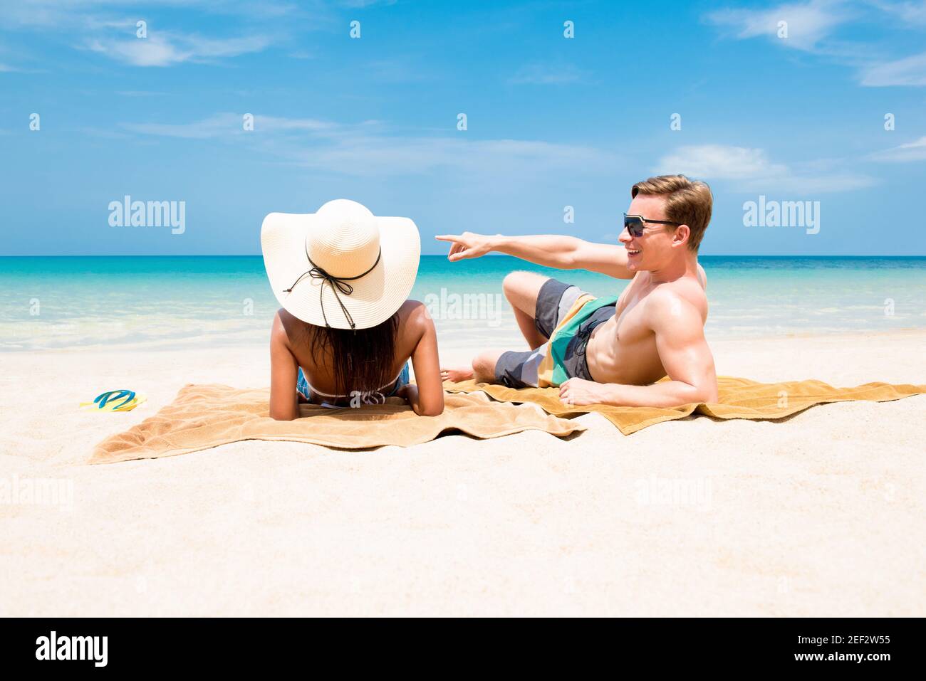 Couple allongé sur une plage de sable blanc relaxant et prenant un bains de soleil en été Banque D'Images
