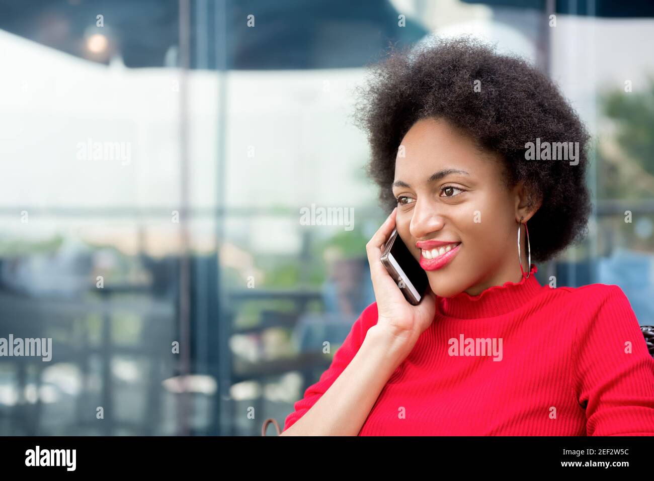 Femme afro souriante appelant sur téléphone mobile dans un café Banque D'Images