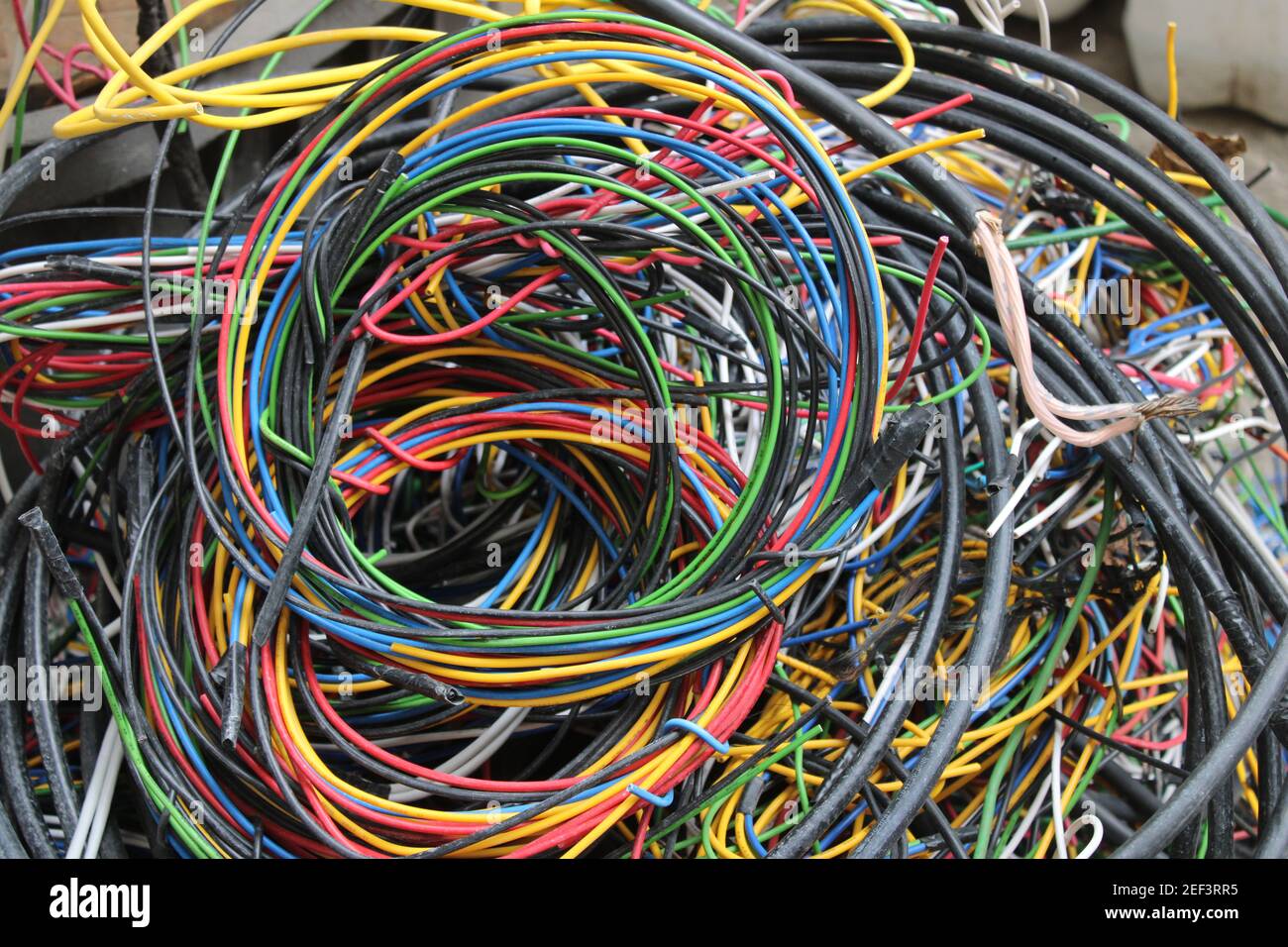 Fils et câbles multicolores enroulés dans un tas derrière un atelier d'électricien local Banque D'Images