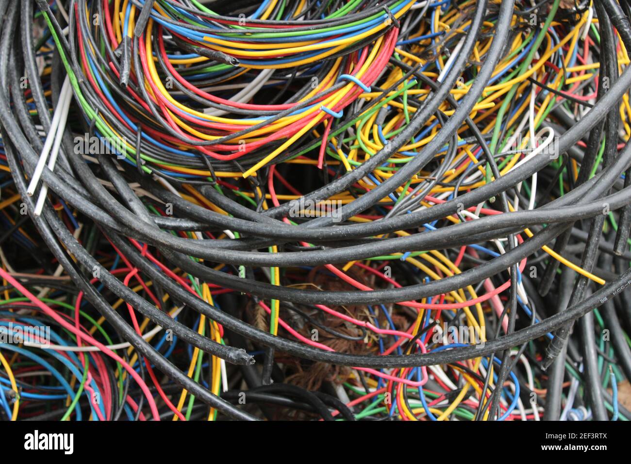 Fils et câbles multicolores enroulés dans un tas derrière un atelier d'électricien local Banque D'Images