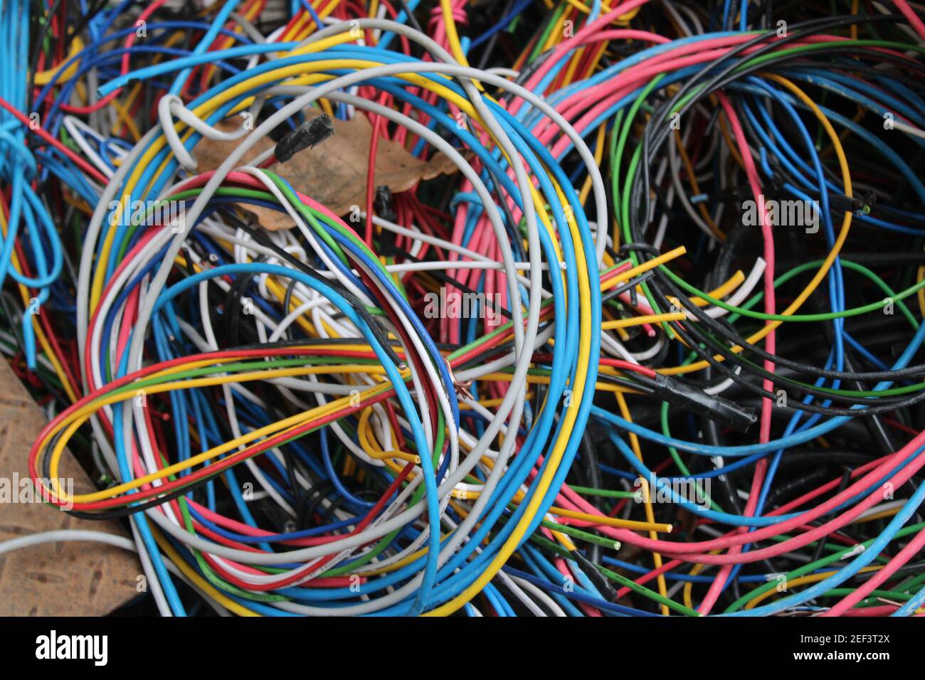 Fils et câbles multicolores enroulés dans un tas derrière un atelier d'électricien local Banque D'Images