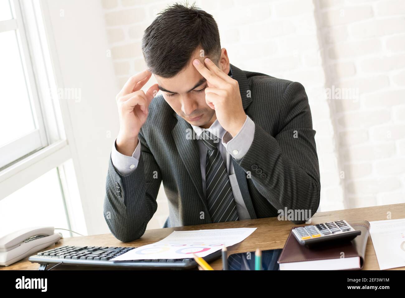 Homme d'affaires sérieux avec des temples de mains, regardant le document financier à table de travail Banque D'Images