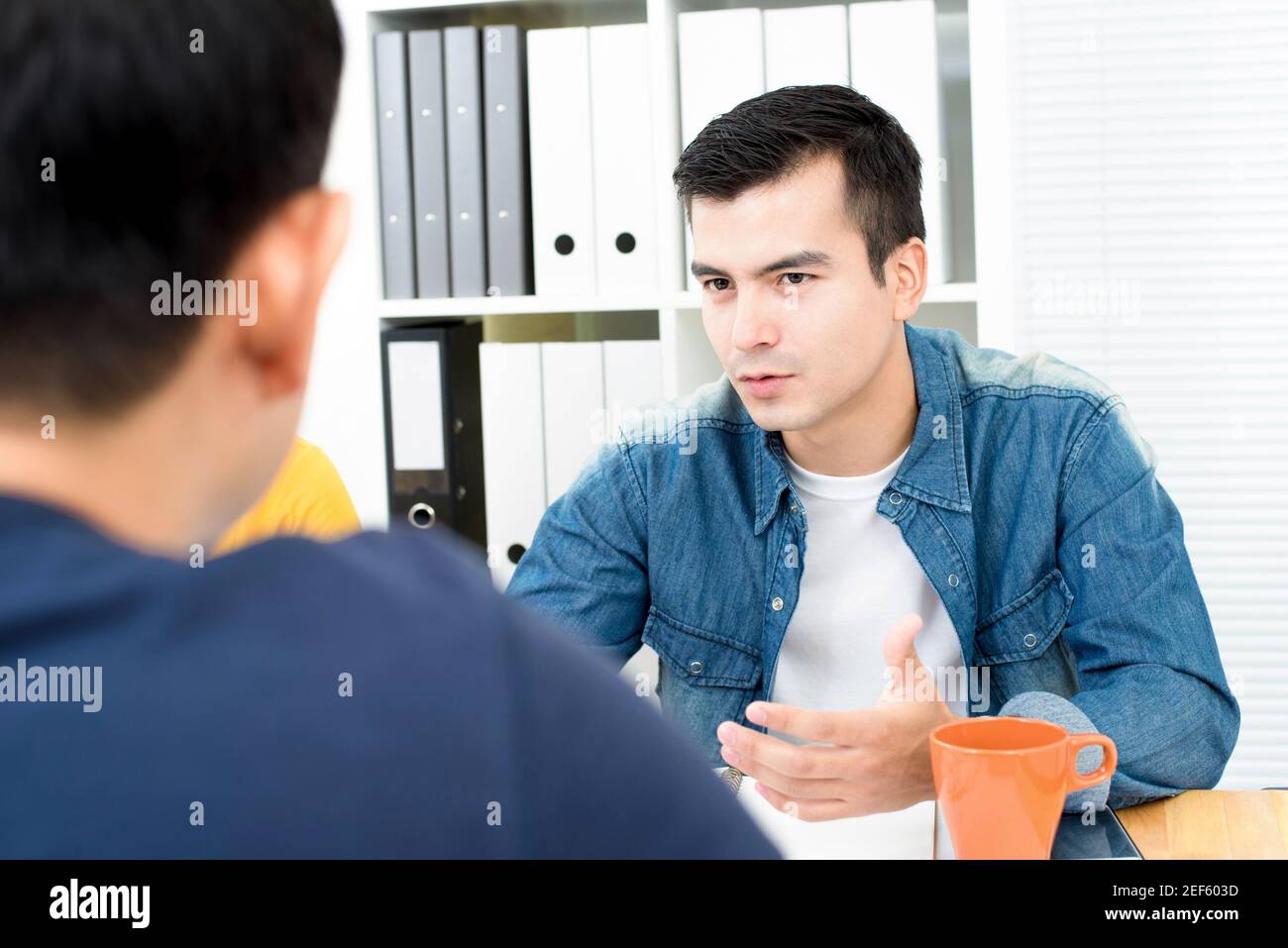 Homme d'affaires décontracté portant une chemise jean discutant du travail au bureau à la table de réunion Banque D'Images