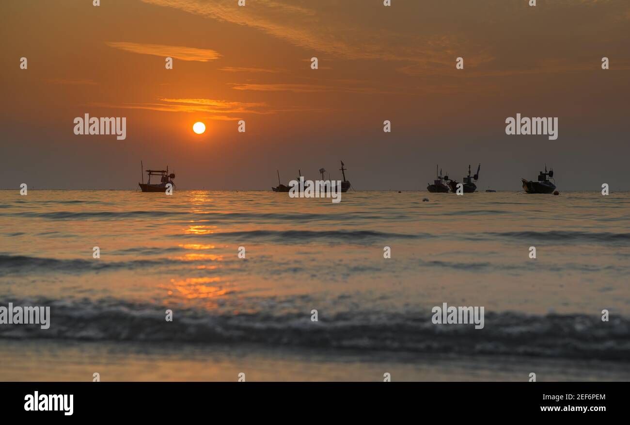 Petits bateaux de pêche dans la mer avec coucher de soleil et lumière chaude et ombre sombre. Banque D'Images