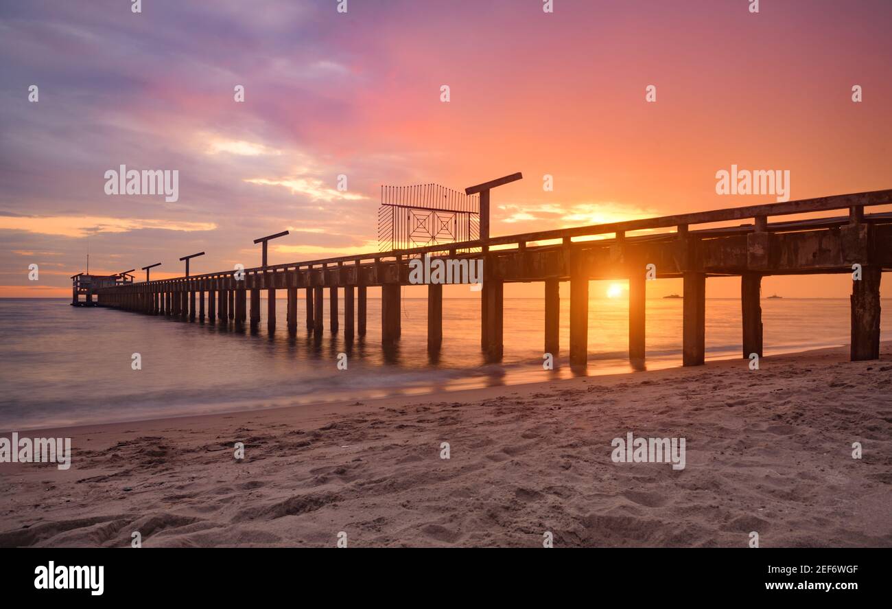 Long pont de mer au coucher du soleil avec lumière chaude et ombre sombre. Banque D'Images