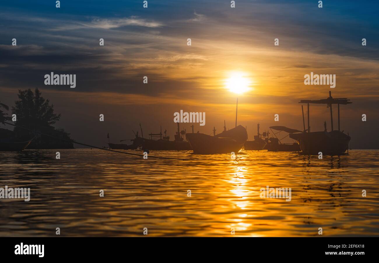 Bateaux de pêche Silhouette dans la mer avec coucher de soleil lumière chaude et ombre sombre. Banque D'Images