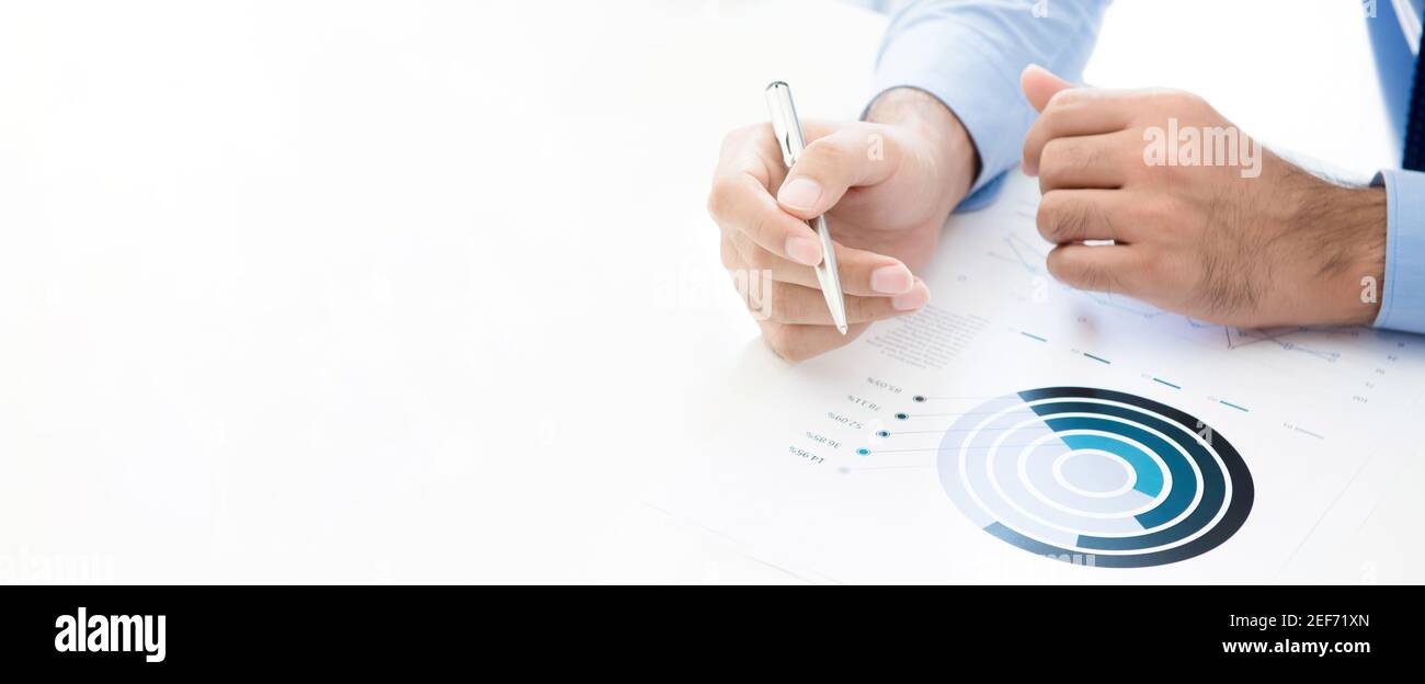 Homme d'affaires tenant le stylo tout en lisant le graphique statistique sur table de travail blanche, bannière panoramique avec espace de copie Banque D'Images