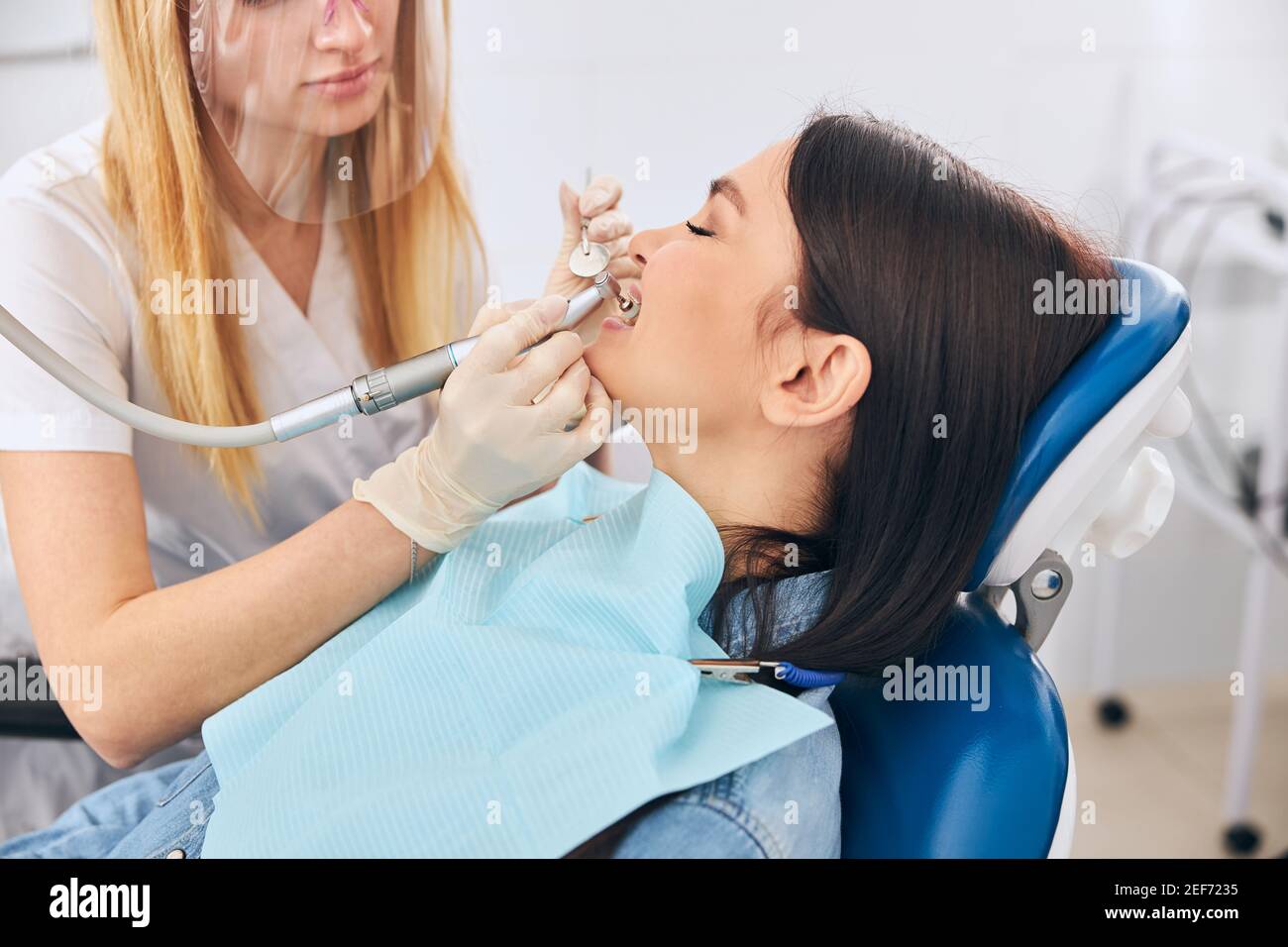 Jeune stomatologiste compétent qui fait la procédure de soins dentaires Banque D'Images