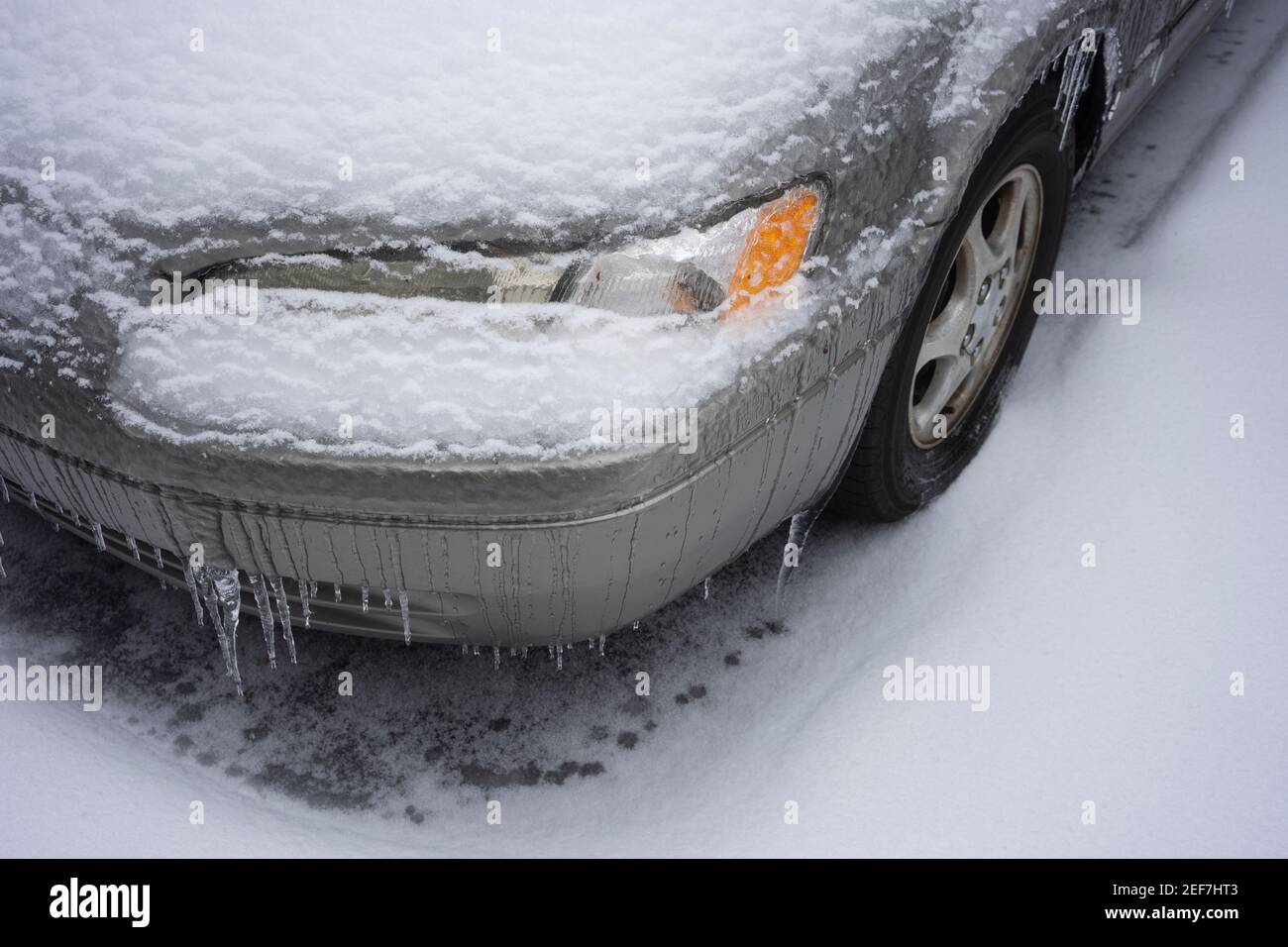 Gros plan du phare gelé d'une voiture après une tempête hivernale avec neige et pluie verglaçante. Banque D'Images