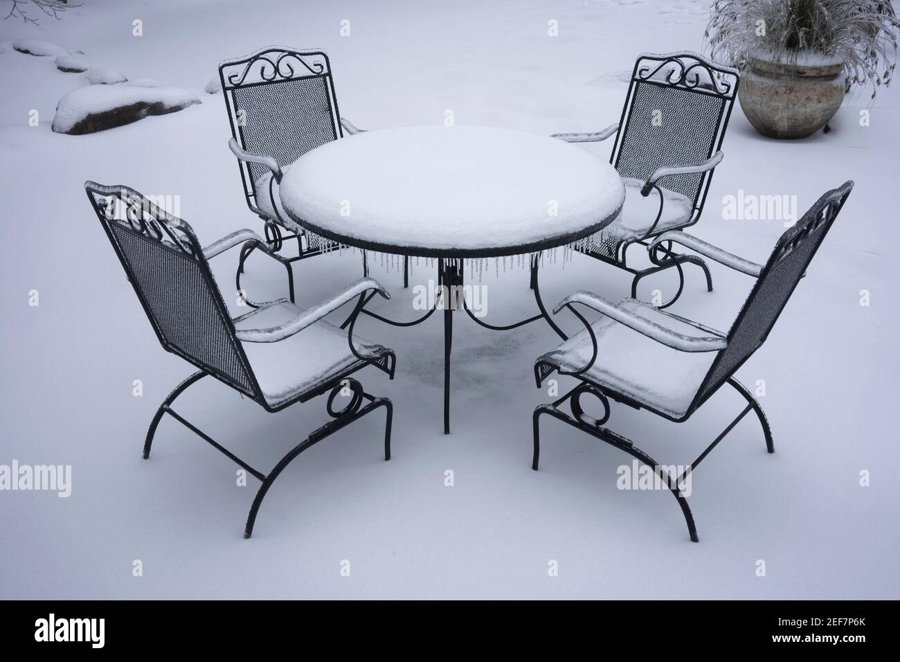 Une table et des chaises de patio extérieures surgelées et enneigées après la neige et la pluie verglaçante en hiver. Banque D'Images