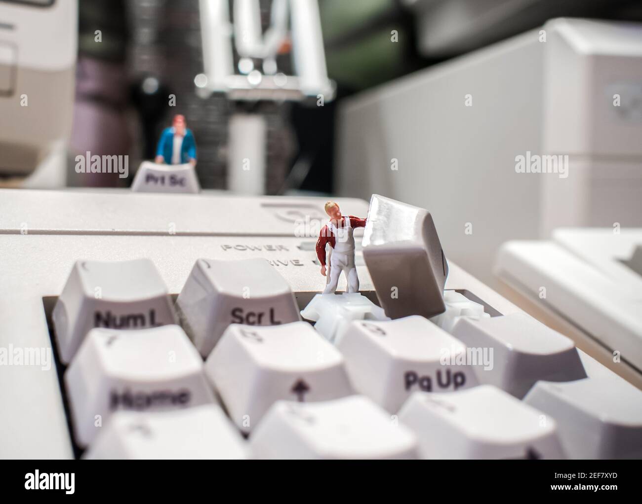 La réparation du clavier informatique est effectuée par de petits techniciens Clé retirée du PC pour nettoyer la balance personne modèle dans la réparation de vêtements de travail Banque D'Images