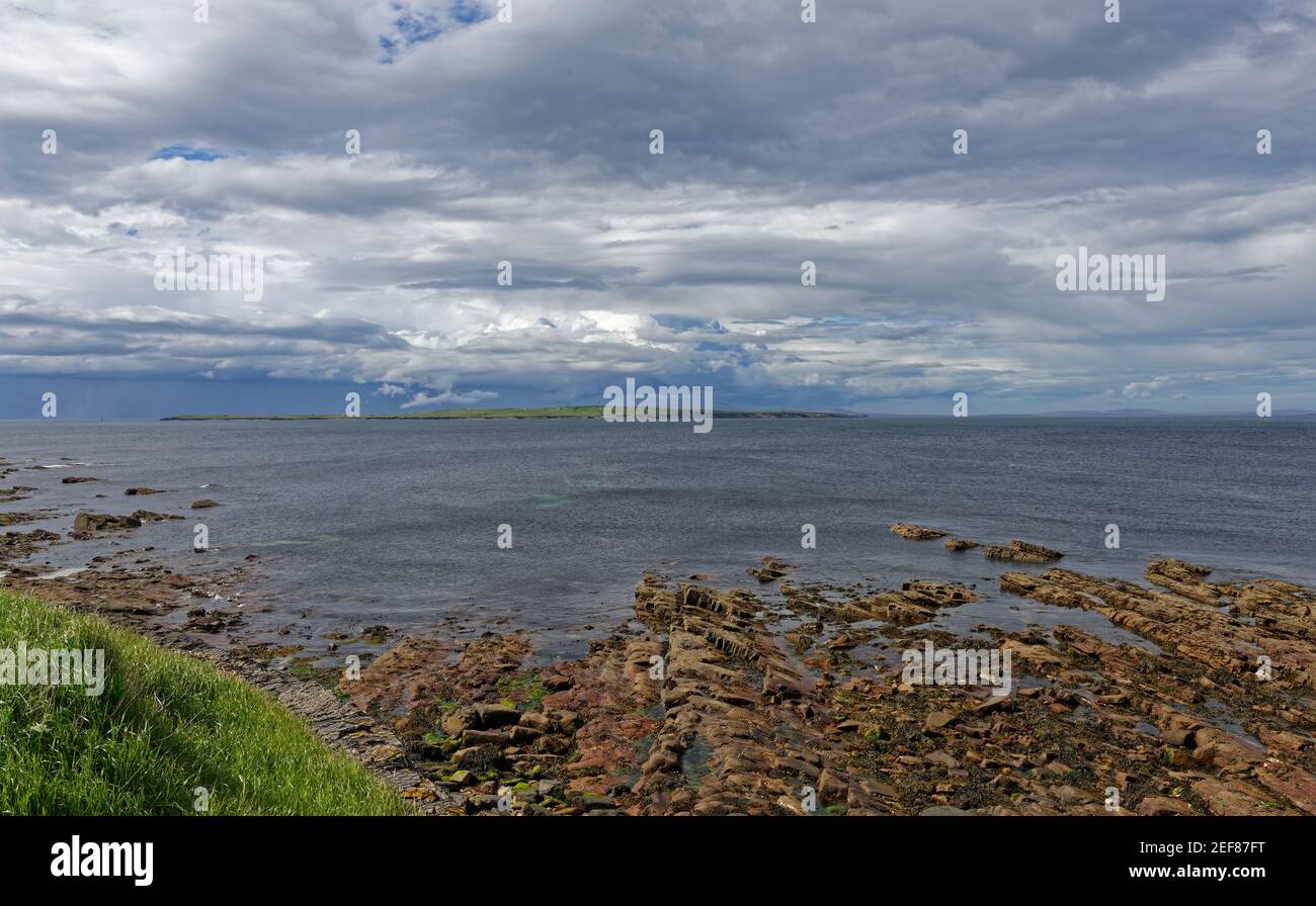 Vue sur l'île de stroma, une partie des Orkneys depuis la plage rocheuse de John OÕGroats en fin d'après-midi en mai. Banque D'Images