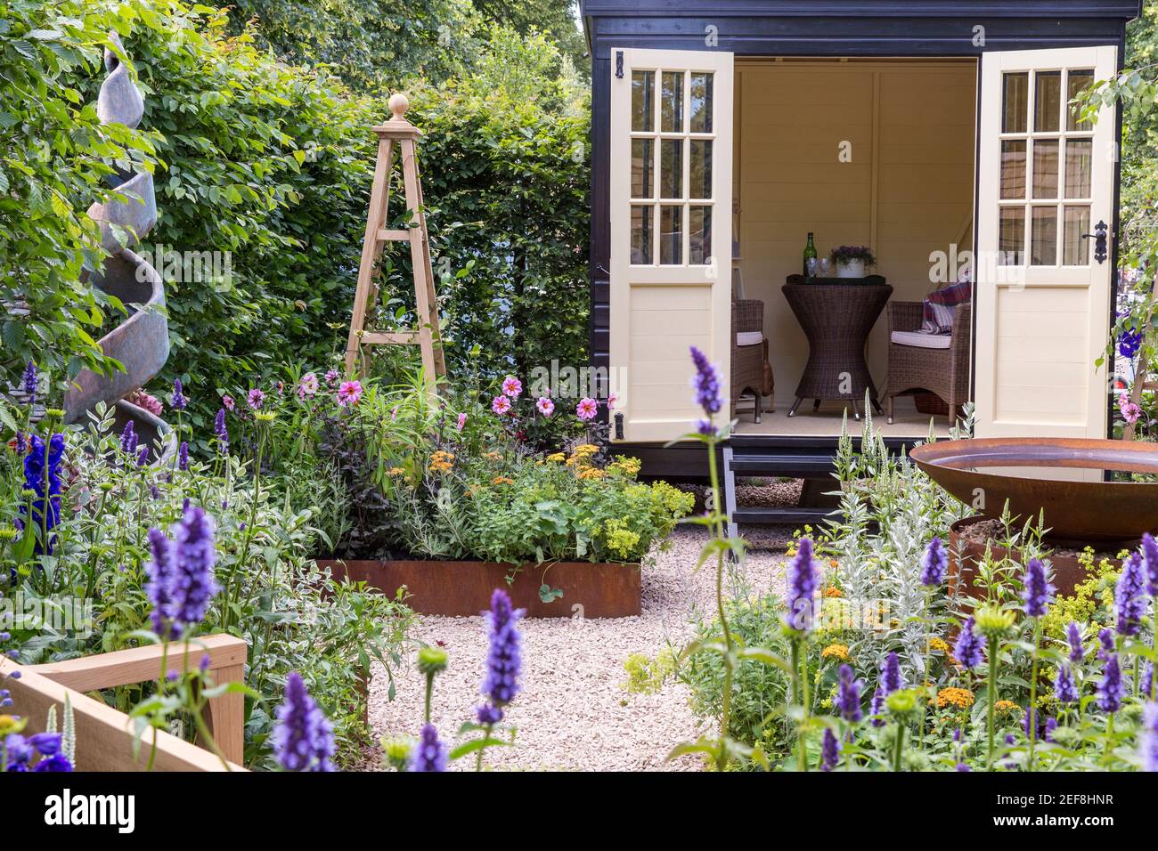 Un petit jardin cottage anglais avec Summerhouse Shepherds Hut dans le jardin de gravier - travail du bureau à domicile - obélisque de bordure de fleur de lit surélevé - Royaume-Uni Banque D'Images
